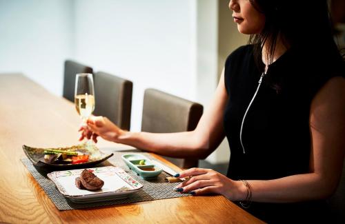 a woman sitting at a table with a glass of wine at Garden Terrace Saga Hotel & Resorts in Saga