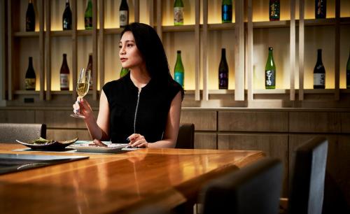 a woman sitting at a table with a glass of wine at Garden Terrace Saga Hotel & Resorts in Saga