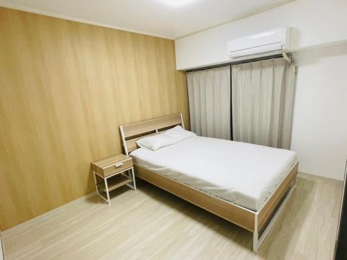 a small bedroom with a bed and a air conditioner at ASUKA HINODECHO ｌ日の出町 in Kusugaurachō