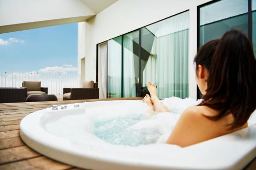 a woman sitting in a bath tub in a building at Garden Terrace Saga Hotel & Resorts in Saga