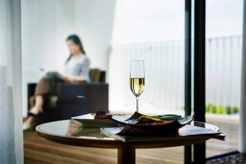 a table with a glass of wine and a plate of food at Garden Terrace Saga Hotel & Resorts in Saga