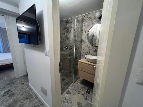 a bathroom with a shower and a sink and a television at דירת גן על הים בנהריה in Nahariyya