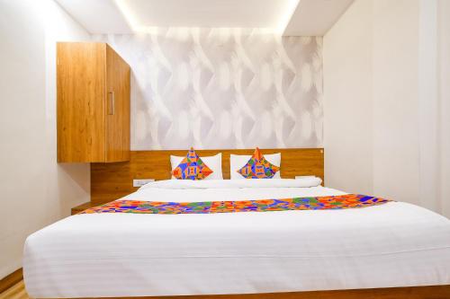 um quarto com uma grande cama branca com almofadas coloridas em FabHotel Woodlark Inn em Indore