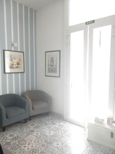 a living room with two chairs and a window at Door Eight in Il-Furjana