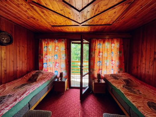 a bedroom with two beds and a window with curtains at Hunting lodge under the rock and the river Kretinka in Bystré