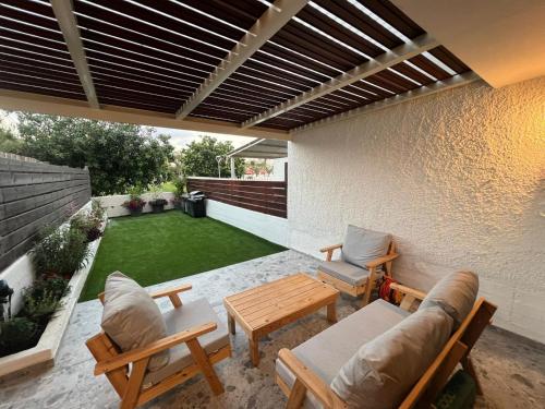 eine Terrasse mit einem Tisch und Stühlen sowie einer kleinen Liegewiese in der Unterkunft דירת גן על הים בנהריה in Naharija