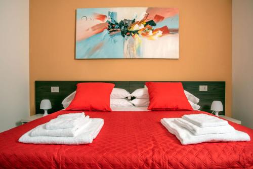 uma cama vermelha com duas almofadas vermelhas e um quadro em Camelot Red - Appartamenti em Verona