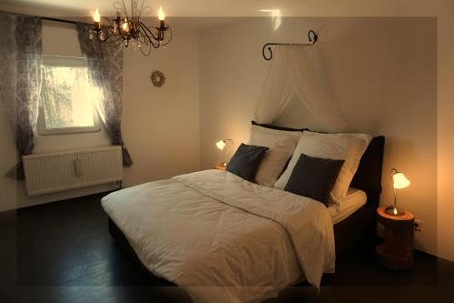 1 dormitorio con 1 cama blanca grande con lámpara de araña en Relaxhome en Lindlar