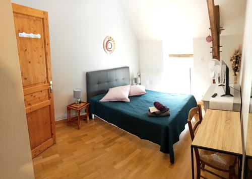 Schlafzimmer mit einem Bett mit blauer Bettwäsche und rosa Kissen in der Unterkunft La haye Georget in Feneu