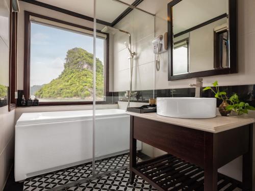 a bathroom with a tub and a sink and a mirror at Rosa Cruise in Ha Long