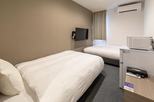 a hotel room with two beds and a tv at HOTEL R9 The Yard Ishioka in Ishioka