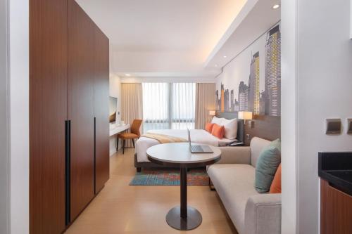 a hotel room with a bed and a couch and a table at Citadines Benavidez Makati in Manila