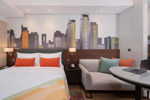 a bedroom with a bed and a couch and a city at Citadines Benavidez Makati in Manila