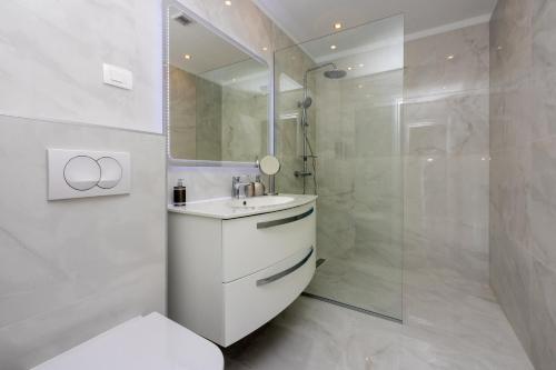 uma casa de banho branca com um lavatório e um chuveiro em Amarie 2 em Dramalj