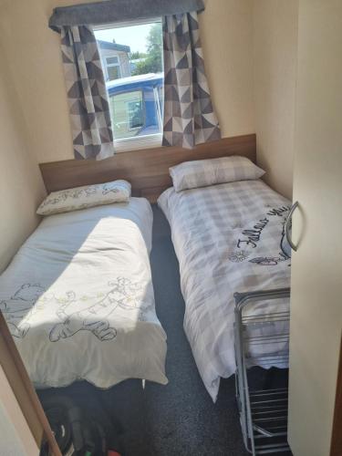 two beds in a room with a window at Seaside Caravan Skipsea Sands in Ulrome