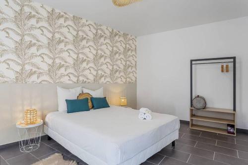 una camera da letto con un grande letto bianco con cuscini blu di Corail, villa 2 chambres à 50 m de la plage de l'Etang-Salé-les-Bains a Étang-Salé les Bains