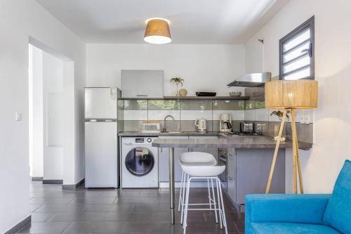 a kitchen with a washing machine and a blue couch at Corail, villa 2 chambres à 50 m de la plage de l'Etang-Salé-les-Bains in Étang-Salé les Bains