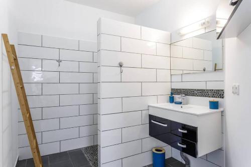 W wyłożonej białymi kafelkami łazience znajduje się umywalka i lustro. w obiekcie Corail, villa 2 chambres à 50 m de la plage de l'Etang-Salé-les-Bains w mieście Étang-Salé les Bains