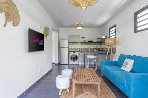 a living room with a blue couch and a table at Corail, villa 2 chambres à 50 m de la plage de l'Etang-Salé-les-Bains in Étang-Salé les Bains