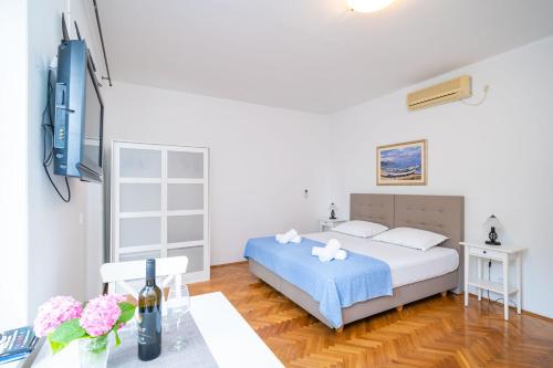 a white bedroom with a bed and a table at Apartments Villa Ivka in Dubrovnik