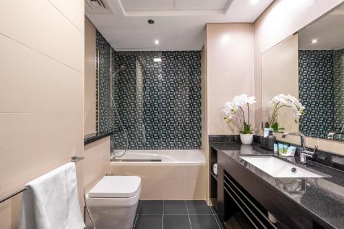 a bathroom with a toilet and a sink and a tub at Luxury Iconic Cayan Tower - Free 5 star Beach Resorts Access! in Dubai