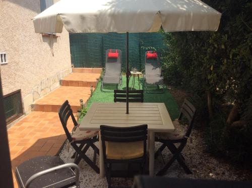 uma mesa e cadeiras sob um guarda-sol num pátio em Un petit coin sympa em Draguignan