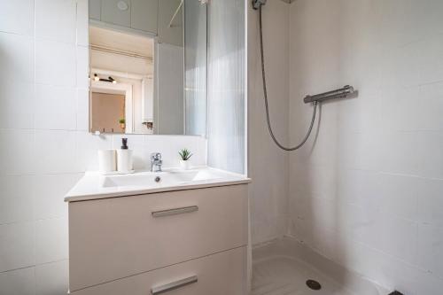 ein weißes Badezimmer mit Waschbecken und Dusche in der Unterkunft Le Zola - charmant 2 chambres - centre gare in Reims