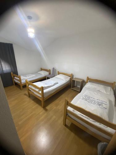two beds in a room with wooden floors at Hostel Heimli in Pristina