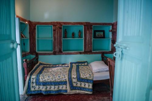 Bristows Haveli Homestay في جودبور: غرفة نوم بسرير بالحوائط الزرقاء والرفوف