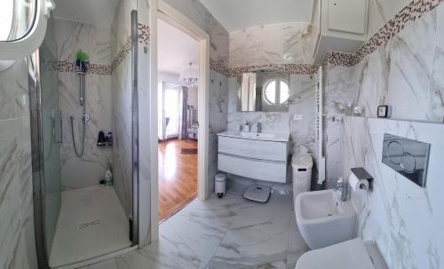 La salle de bains blanche est pourvue d'un lavabo et d'une douche. dans l'établissement Dernier étage d'une maison, à Roquebrune-Cap-Martin