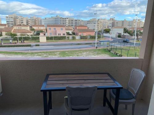 una mesa y sillas en un balcón con vistas a la ciudad en Joli studio cabine confort 28m2 a 200m de la plage, en Canet-en-Roussillon