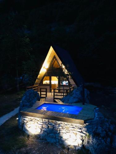 a cabin with a lit up pool in the night at Etno apartmani Komarnica in Šavnik