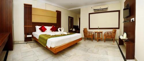 a hotel room with a large bed and a blank screen at SET Residency in Kumbakonam