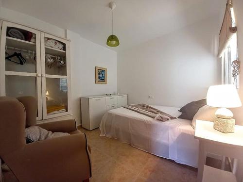 una camera bianca con un letto e una sedia di Awesome cozy bungalow , pool open from june to september a Gran Alacant