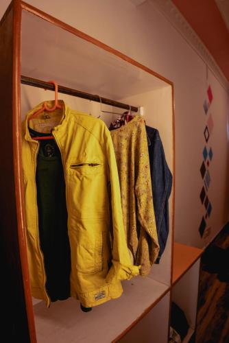 a closet with a yellow jacket and other clothes at Mitra Mcleodganj in McLeod Ganj