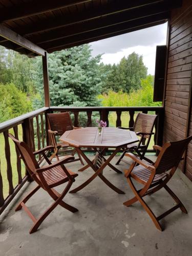 a wooden table and four chairs on a porch at Sarni Zakątek in Rybno