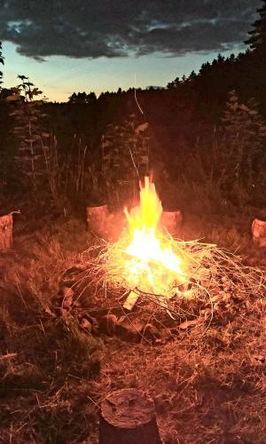 a fire burns in a field at sunset at Sarni Zakątek in Rybno