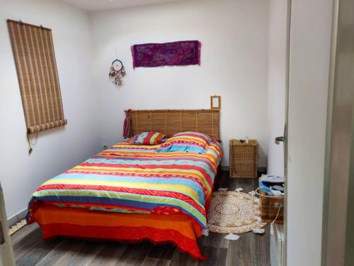 1 dormitorio con 1 cama con una manta colorida en Maison d'une chambre avec jardin clos a Arsac en Arsac