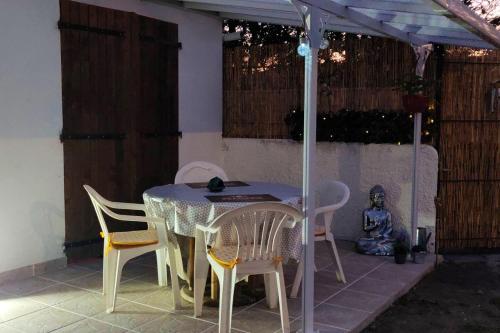 una mesa con sillas y una sombrilla en el patio en Maison d'une chambre avec jardin clos a Arsac en Arsac