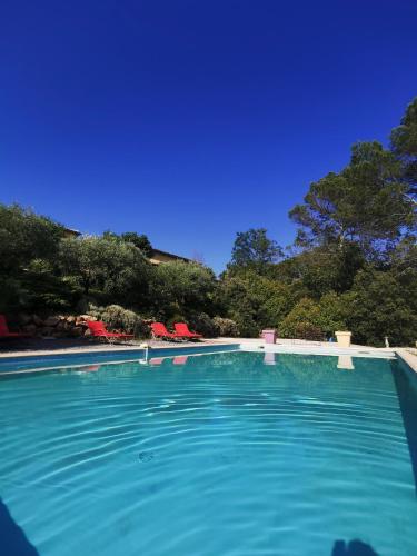 a swimming pool with blue water and red chairs at Bastide Saint Bernard in Le Thoronet