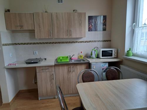 eine Küche mit Holzschränken, einem Tisch und einer Mikrowelle in der Unterkunft Apartament Borowiacki in Tuchola