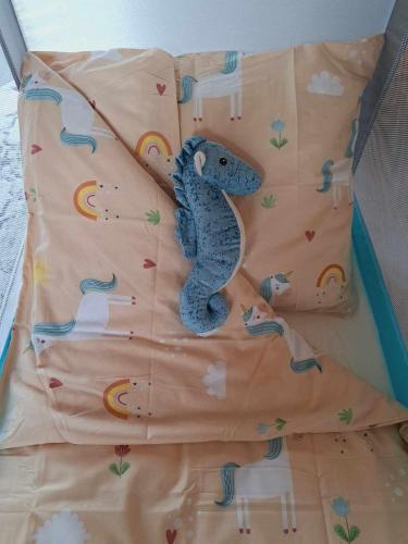a blue stuffed lizard laying on a bed at Domki Na Wzgórzu - domek nr 1 in Mrągowo