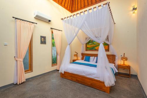 a bedroom with a canopy bed with white drapes at villa ambara sumberkima in Banyuwedang