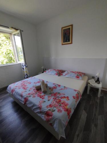 a bedroom with a bed with red flowers on it at Konavle Village Apartment in Čilipi