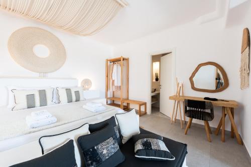 Habitación blanca con cama, mesa y sillas en Sersi Paros Villas & Suites en Kampos Paros