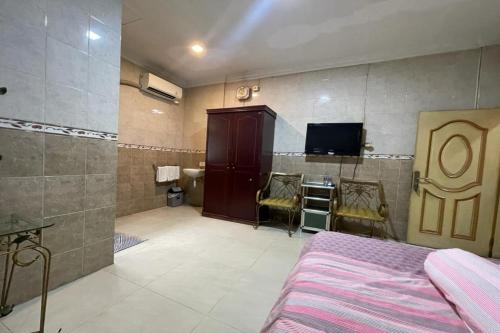 een slaapkamer met een bed en een televisie en een badkamer bij OYO 92772 Losmen Diah Syariah in Langsa