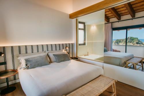 a bedroom with a bed and a tub and a window at Casa Indiana Hotel Boutique in Blanes