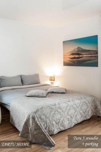 a white bedroom with a bed with a picture on the wall at City Center Turu str apartments, parking, Tartu Home in Tartu