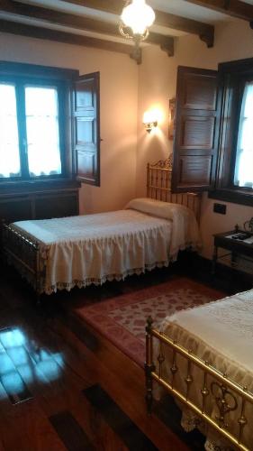 a bedroom with two beds and two windows at Casa Rural La Huerta in Riaño
