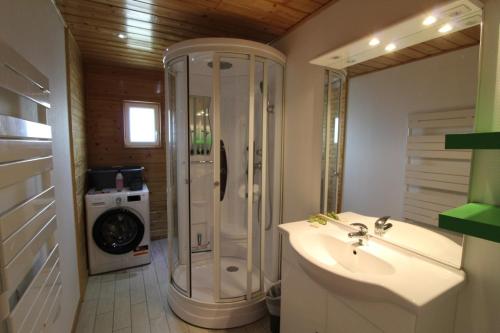 a bathroom with a shower and a sink and a washing machine at Apt 1er étage Chalet Au coteau des xette in Gérardmer